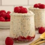 Jar filled with high-protein overnight oats and topped with raspberries.