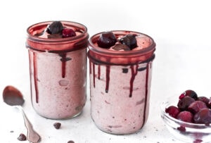 Two chocolate covered cherry smoothies topped with chocolate and cherries.