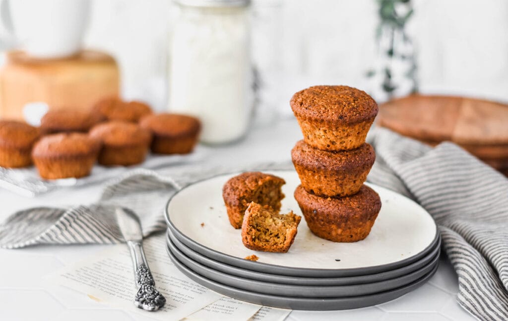 Stack of three paleo espresso banana muffins on a plate with one broken open.