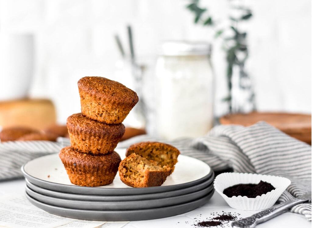 Stack of three paleo espresso banana muffins on a plate with one broken open.