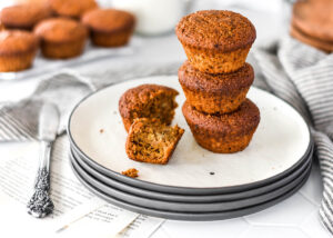 Stack of three paleo banana espresso muffins on a plate with one broken open.