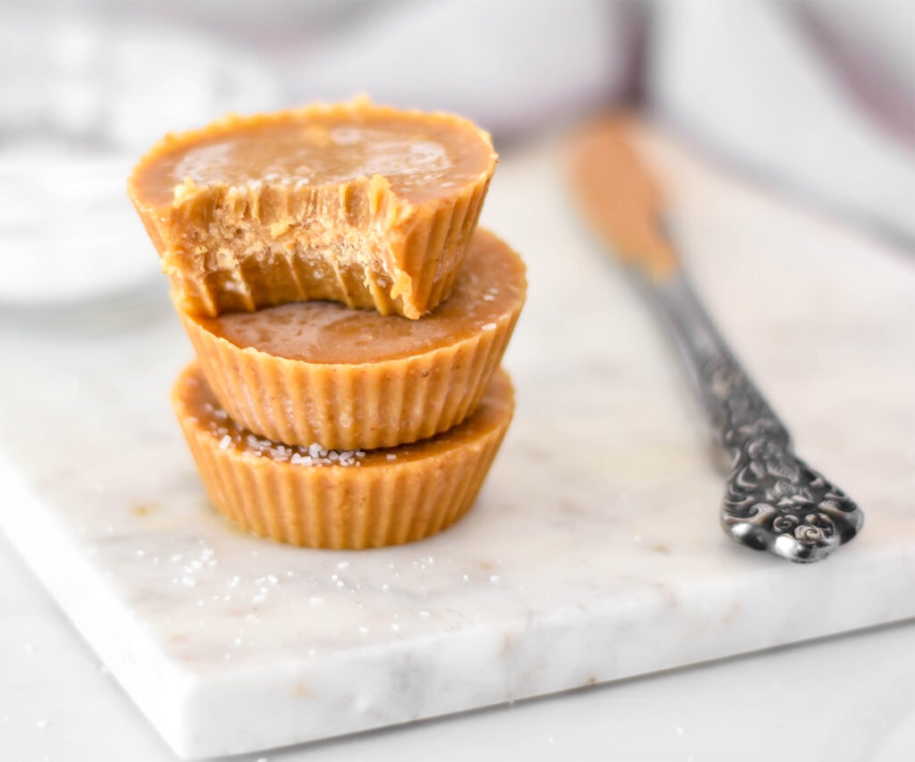 Stack of 3 dairy-free peanut butter fudge cups one with a bite out of it.