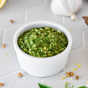 White dish filled with bright green lemon basil pesto.