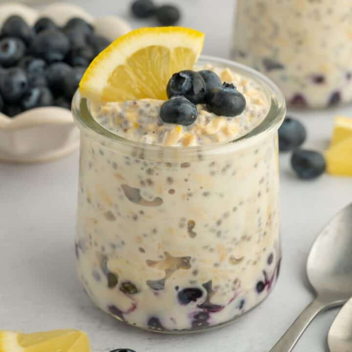 Lemon overnight oats layered with blueberries and topped with blueberries and a slice of lemon.