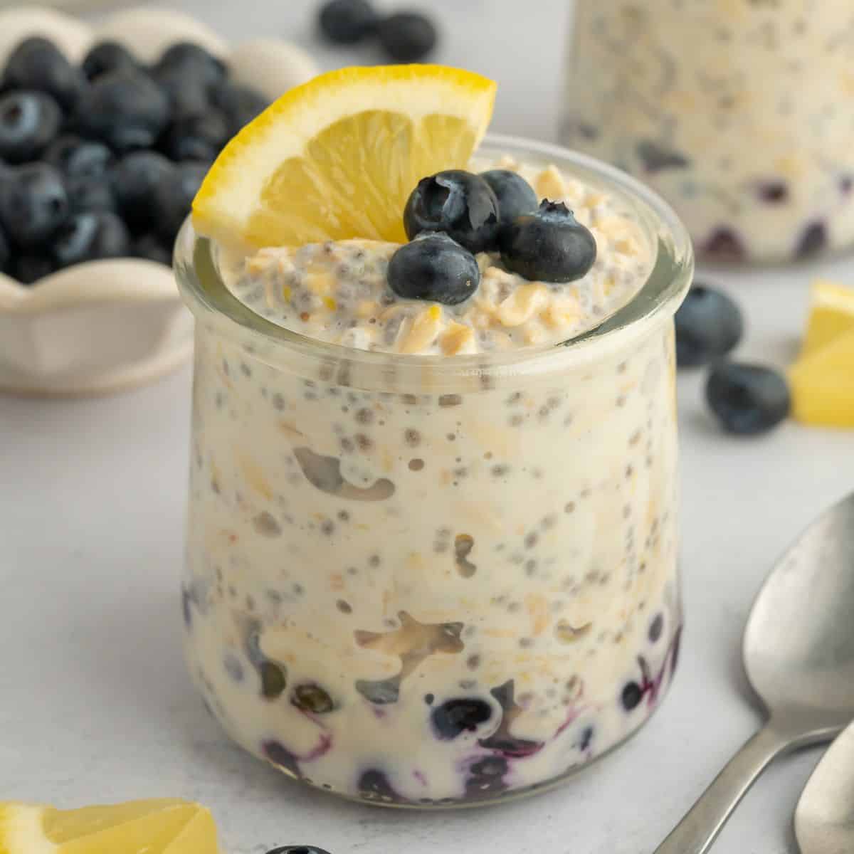 Lemon overnight oats layered with blueberries and topped with blueberries and a slice of lemon.