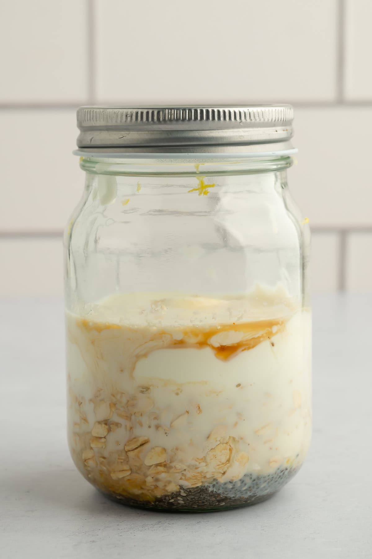 Mixing ingredients for lemon blueberry overnight oats in jar.