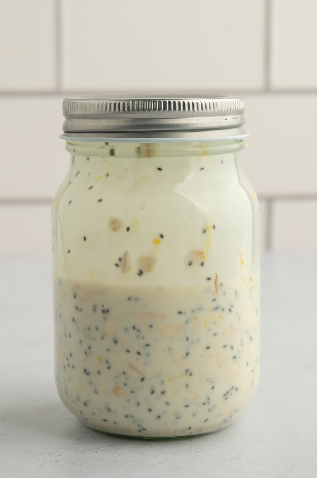 Mixing ingredients for lemon blueberry overnight oats in jar.