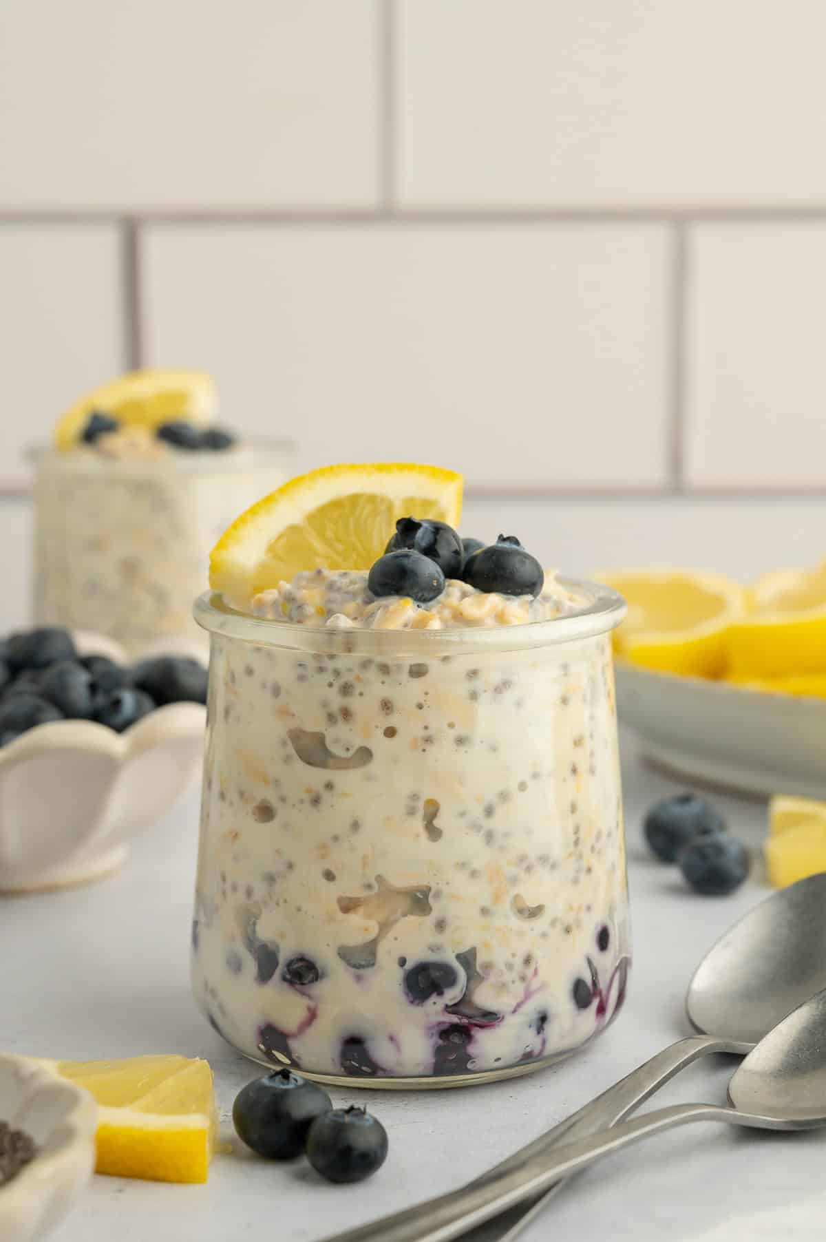 Lemon overnight oats layered with blueberries and topped with blueberries and a slice of lemon.