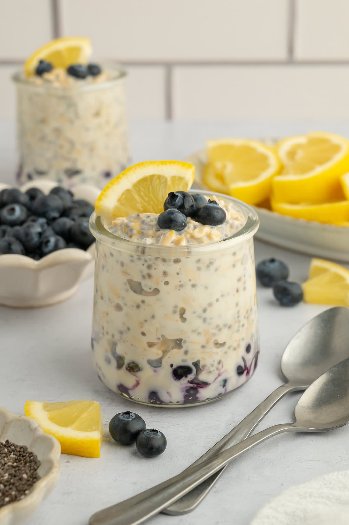 Lemon overnight oats layered with blueberries and topped with blueberries and a slice of lemon.