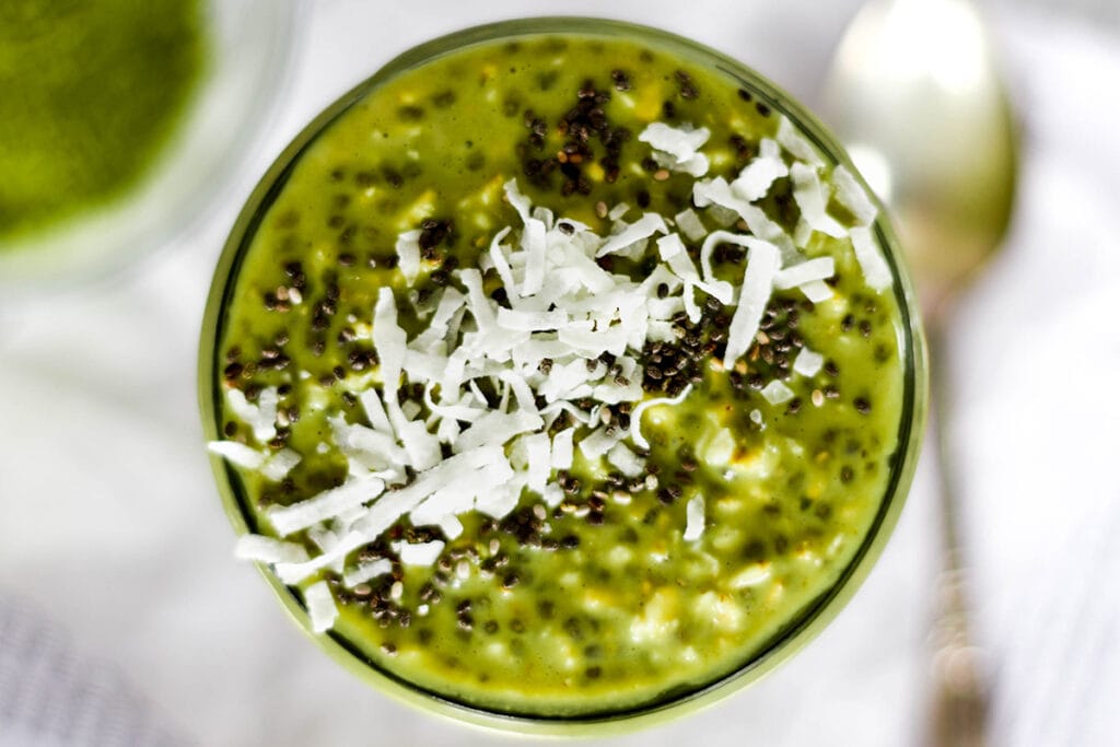 Top down view of bright green mactha overnight oats topped with coconut and chia seeds.