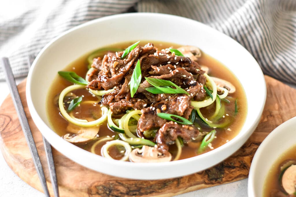 Bowl of bone broth with zucchini noodles and paleo bulgogi.