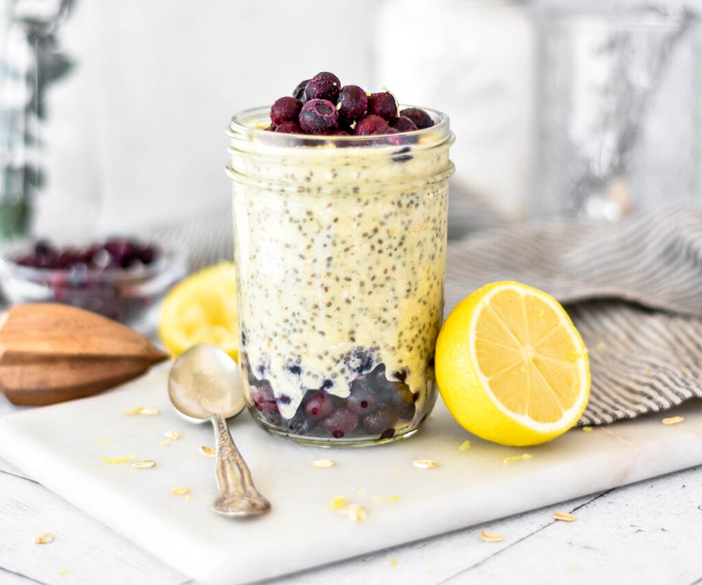 Mason jar filled with lemon overnight oats with blueberries layered in.