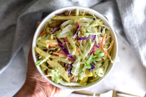 Bowl of brightly colored coleslaw with cabbage.