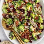 Platter with broccoli crunch salad and serving utensils.