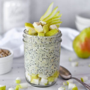 Pear overnight oats in mason jar next to a pear and a bowl of oats.