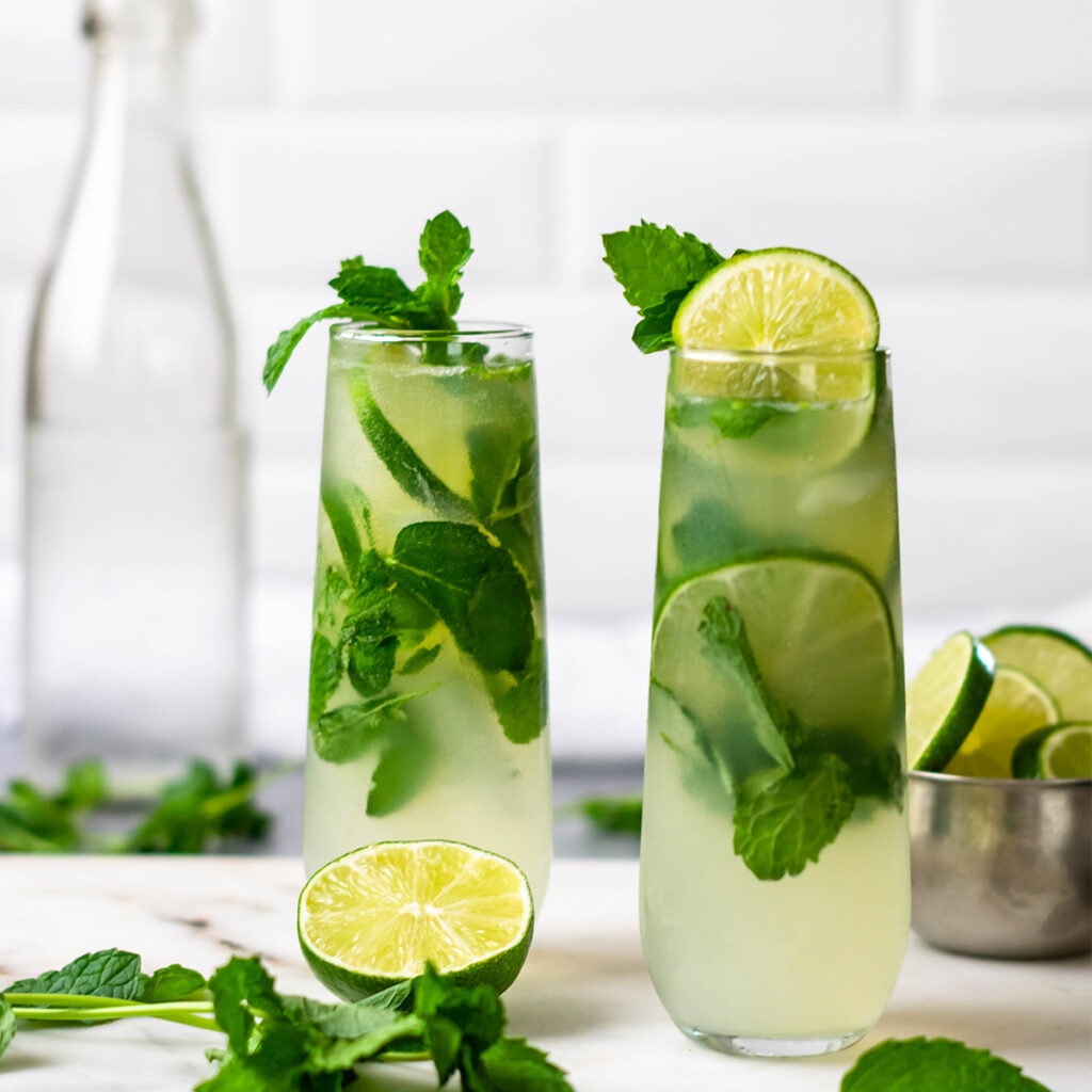 Two keto mojitos garnished with lime and mint.