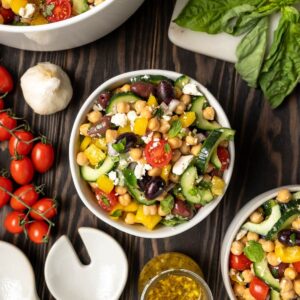 Bowl of chickpea salad with feta, olives bright red cherry tomatoes and cucumber.