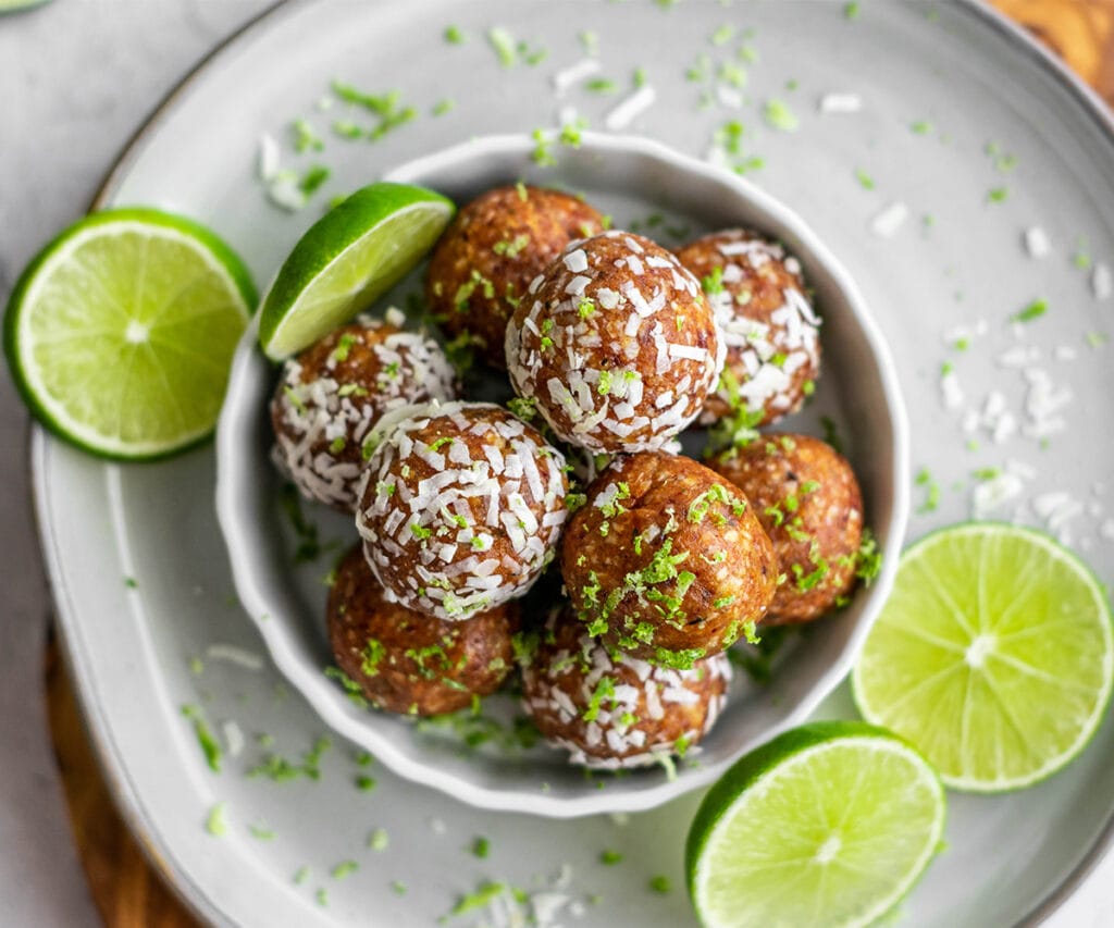 Dish filled with key lime pie energy balls covered in coconut and lime zest.