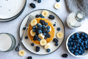 Top down view of vegan oat pancakes loaded with berries and banana slices.