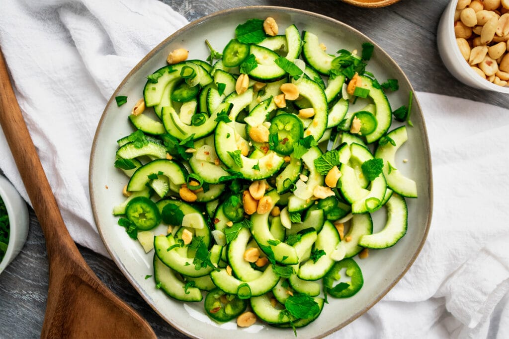 Plate of Vietnamese cucumber salad made of cucumber, mint, ccilantro, green onion and peanuts.