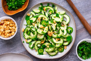 Plate of Vietnamese cucumber salad made of cucumber, mint, ccilantro, green onion and peanuts.