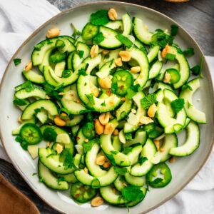 Plate of Vietnamese cucumber salad made of cucumber, mint, ccilantro, green onion and peanuts.