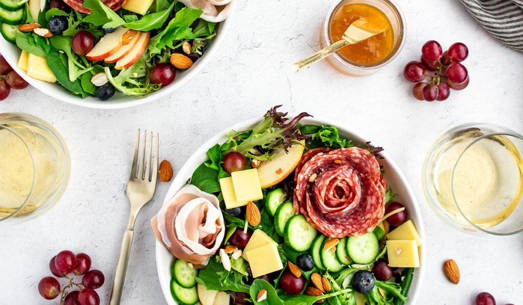 Charcuterie salad with nuts, salami, cheese, grapes, blueberries, olives and cucumbers.