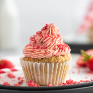 Keto Strawberry Cupcakes covered with bright red forsting and freeze dried strawberry crumbs.