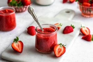 Jar of low carb strawberry sauce with an antique spoon in it.
