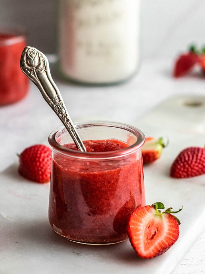 Jar of keto strawberry sauce with an antique spoon in it.
