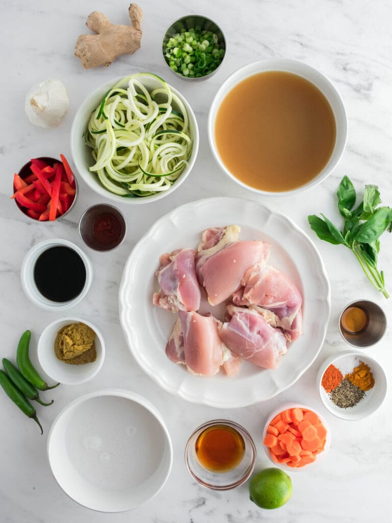 Picture of coconut milk, spices, curry paste, ginger, garlic, chicken thighs, zucchini noodles, bell pepper, carrots, green onions, basil, sesame oil, coconut aminos, chili paste, fish sauce and lime.