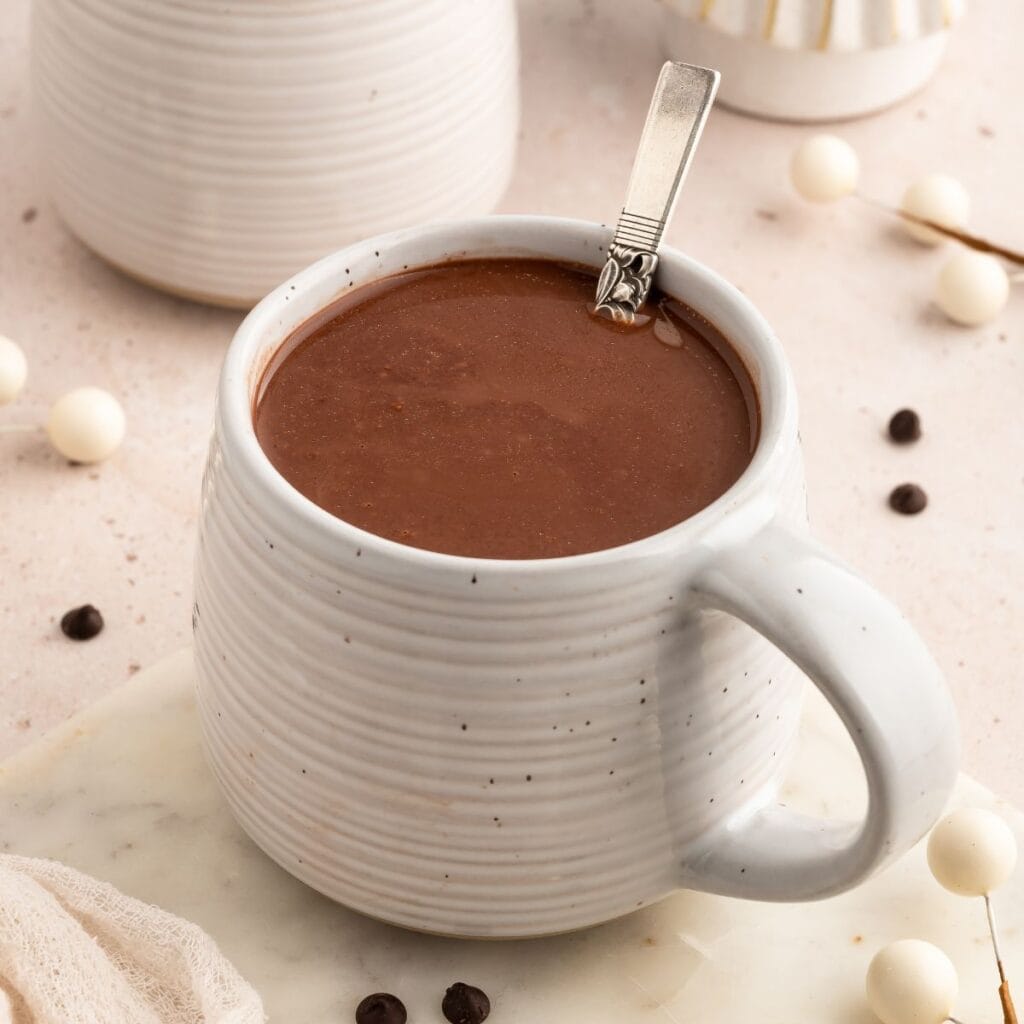 Ceramic cup of hot chocolate with a spoon in it.