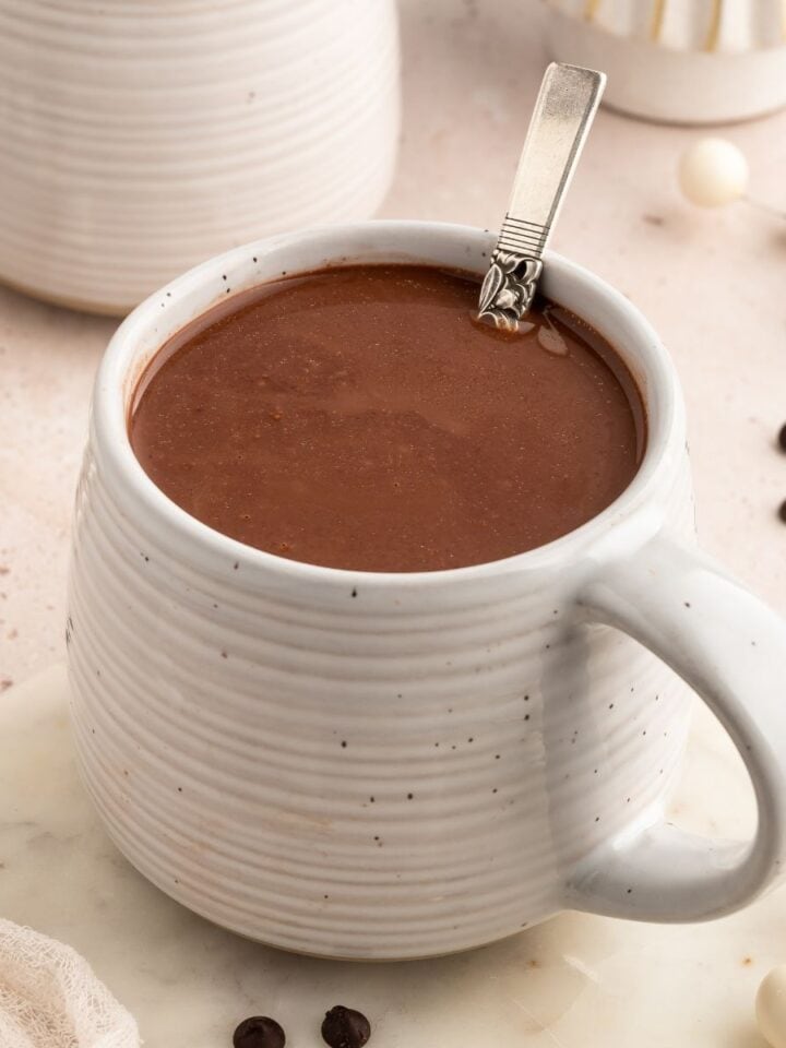 Ceramic cup of hot chocolate with a spoon in it.