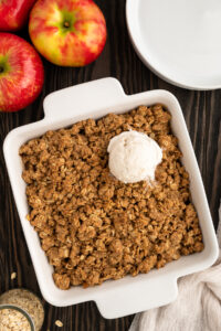 Baking dish of gluten-free Peanut butter apple crisp topped with ice cream.