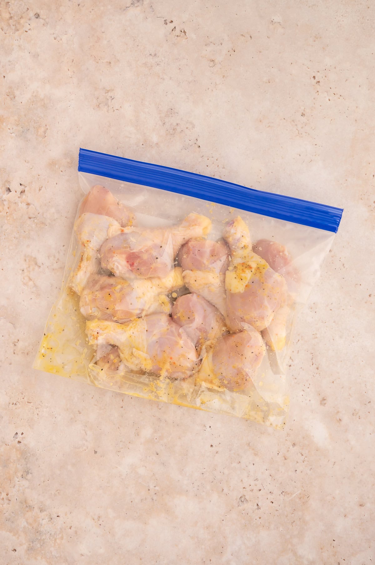 Chicken drumsticks in a resealable bag with lemon pepper marinade.