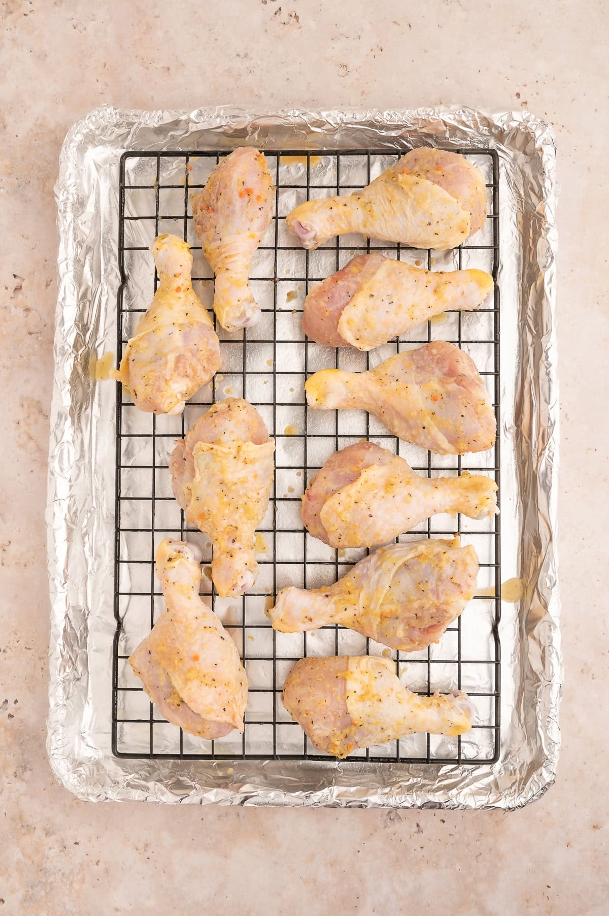 Uncooked chicken drumsticks on a sheet pan.
