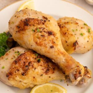 Lemon pepper drumsticks on a plate with parley and lemon slices.