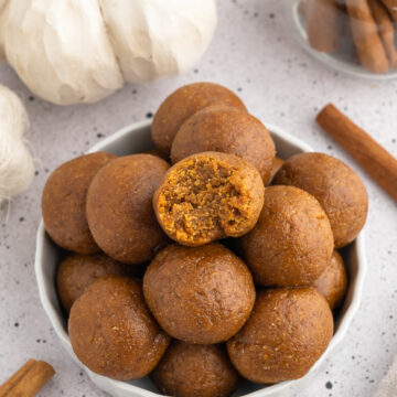 Pile of pumpkin protein balls one with a bite out of it.