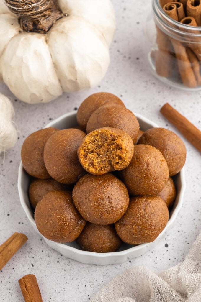 Pile of pumpkin protein balls one with a bite out of it.
