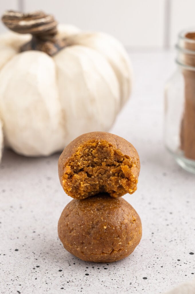 two stacked pumpkin protein balls one with a bite out of it.