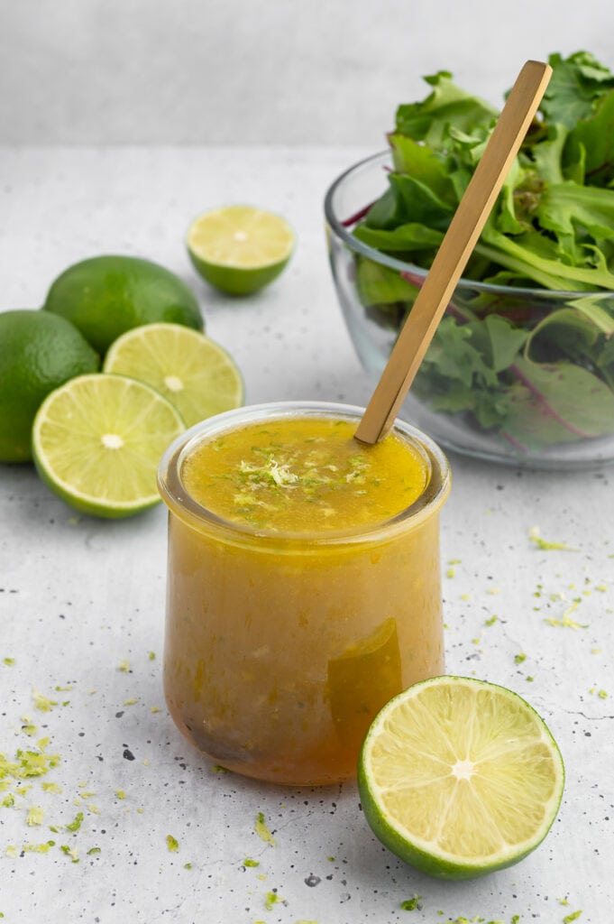 Honey lime dressing in a jar next to limes.