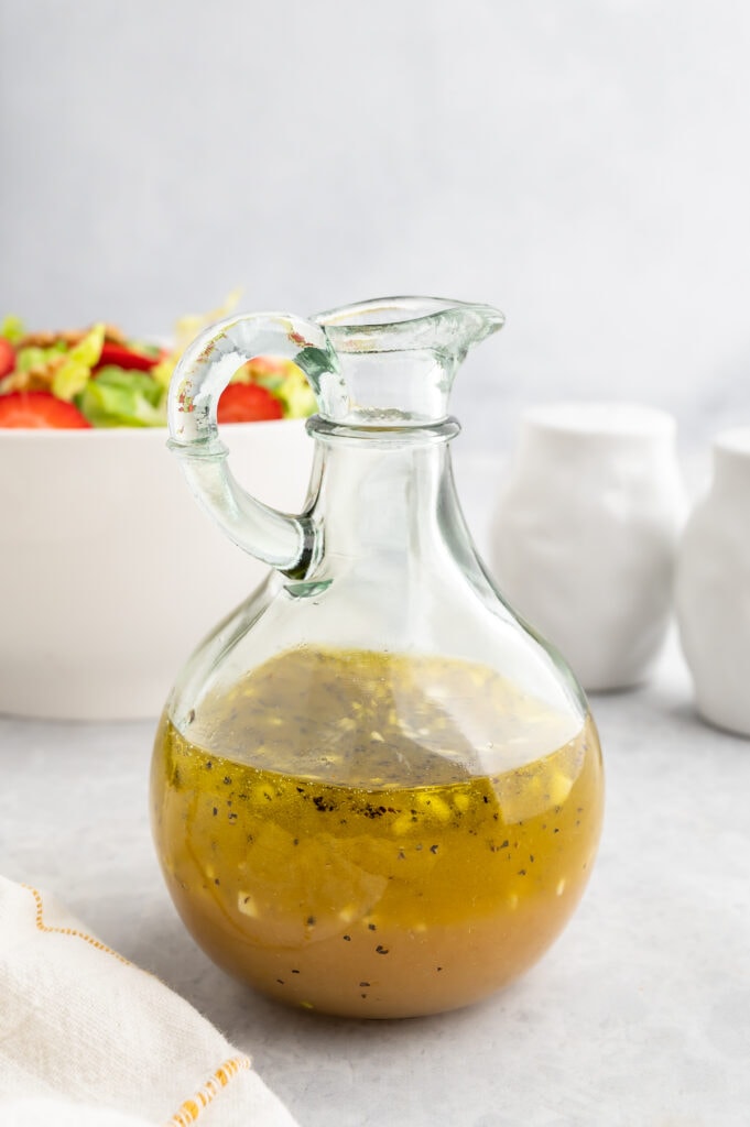 White Balsamic Vinaigrette in a glass jar in front of a salad.