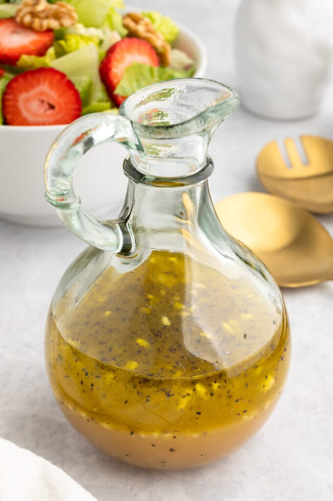 White Balsamic Vinaigrette in a glass jar in front of a salad.