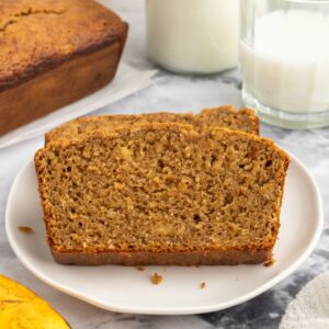 Almond Butter Banana Bread on a plate next to milk and bananas.