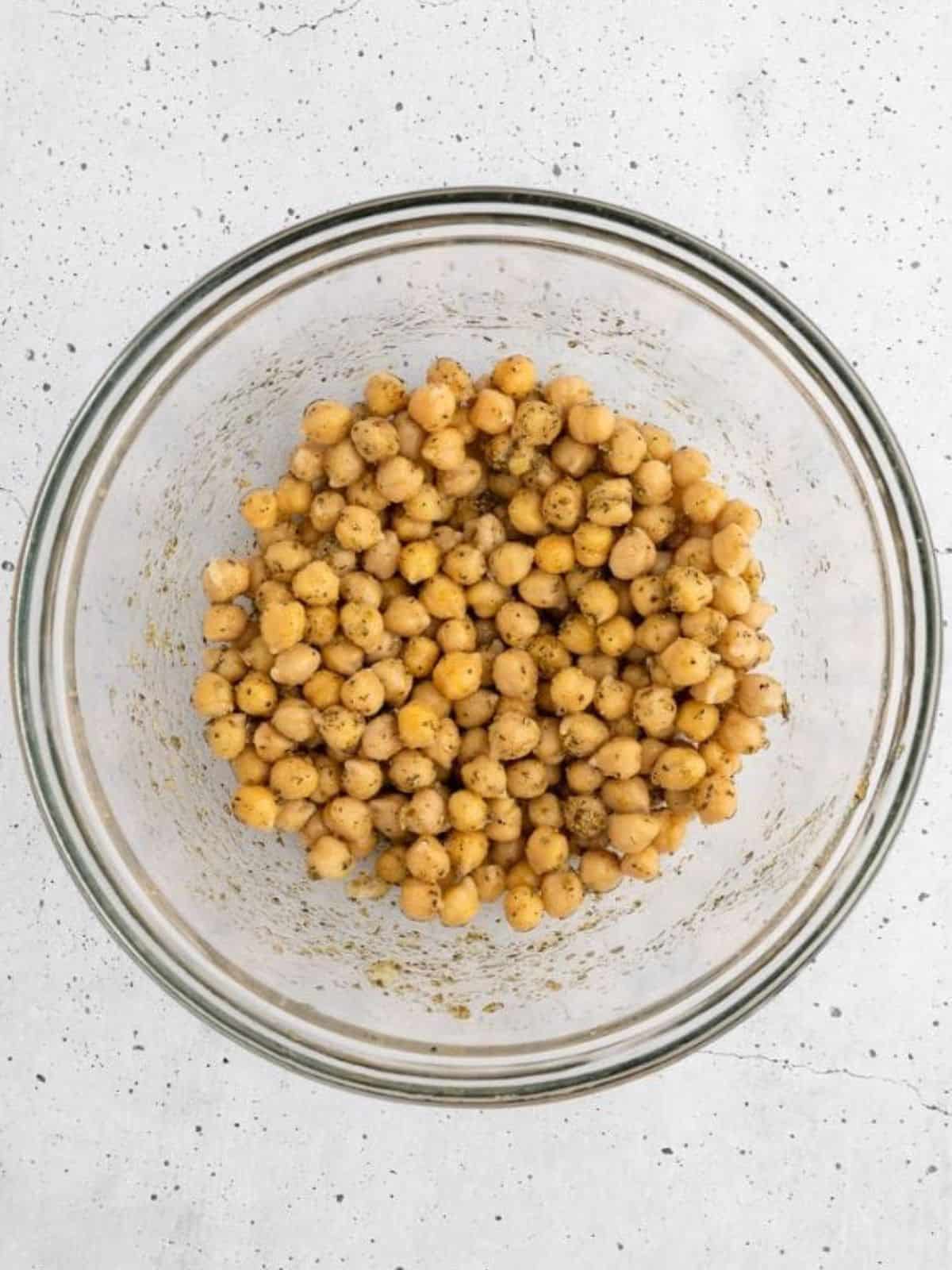 Mixing chickpeas with herbs, spices, lemon juice, and olive oil.