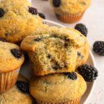 Pile of gluten-free blackberry muffins, one with a bit out of it.