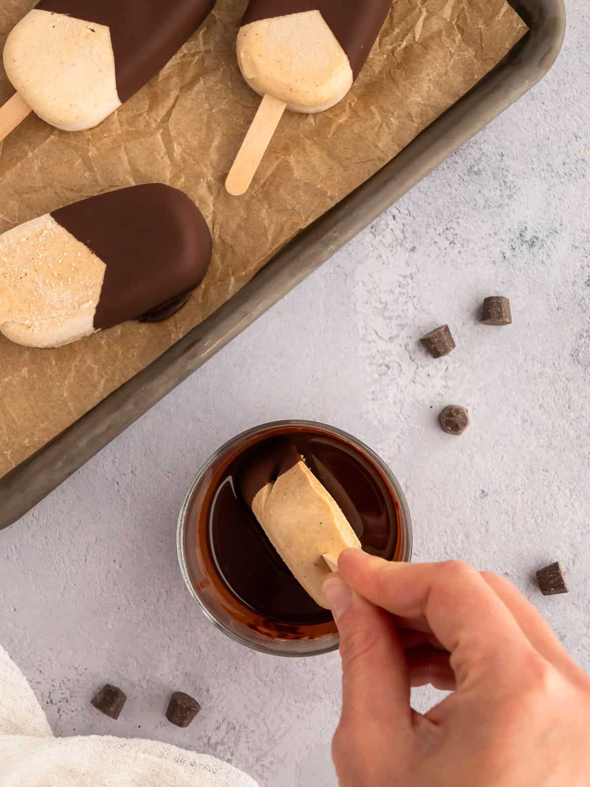 Dipping frozen protein ice cream bars in chocolate.