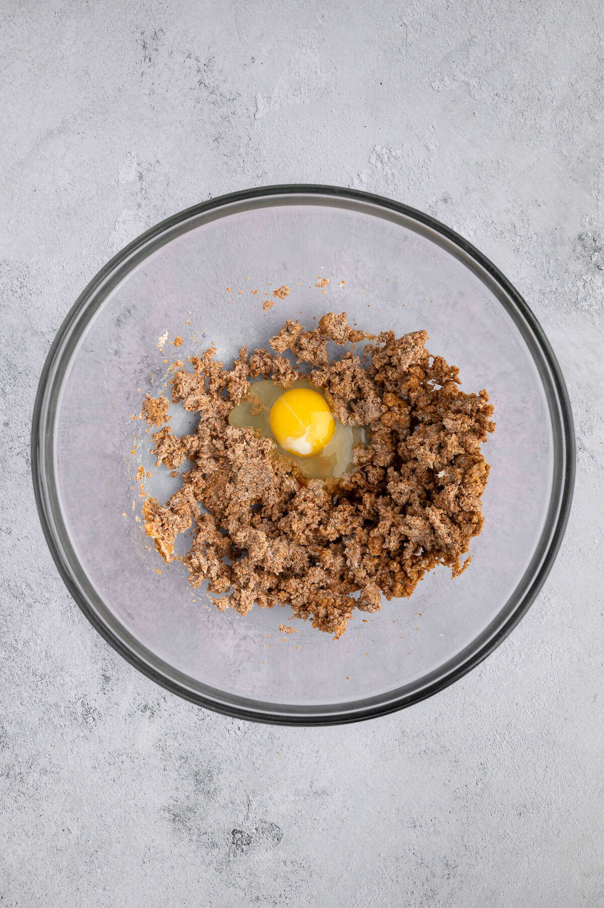 Adding egg and vanilla to mixing bowl with butter and brown sugar.