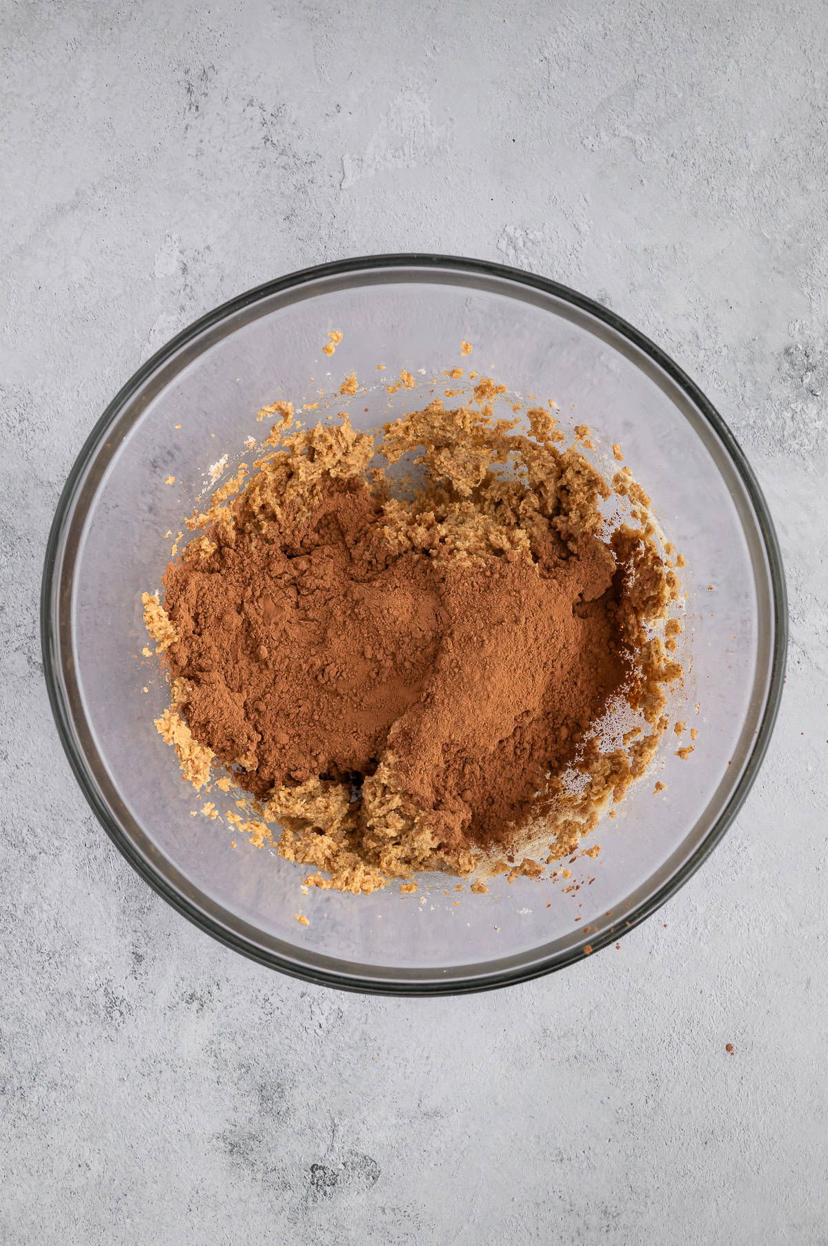 Adding cocoa powder to dough in mixing bowl.