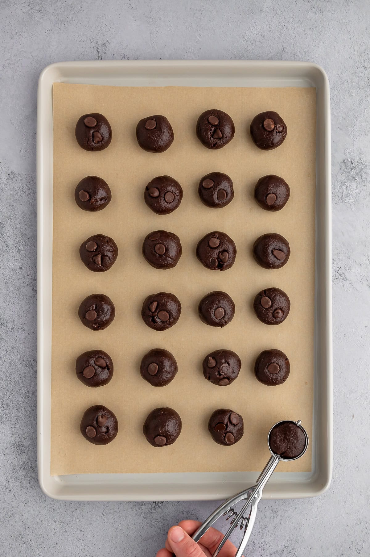 Scooping cookie dough into balls and placing on baking sheet.